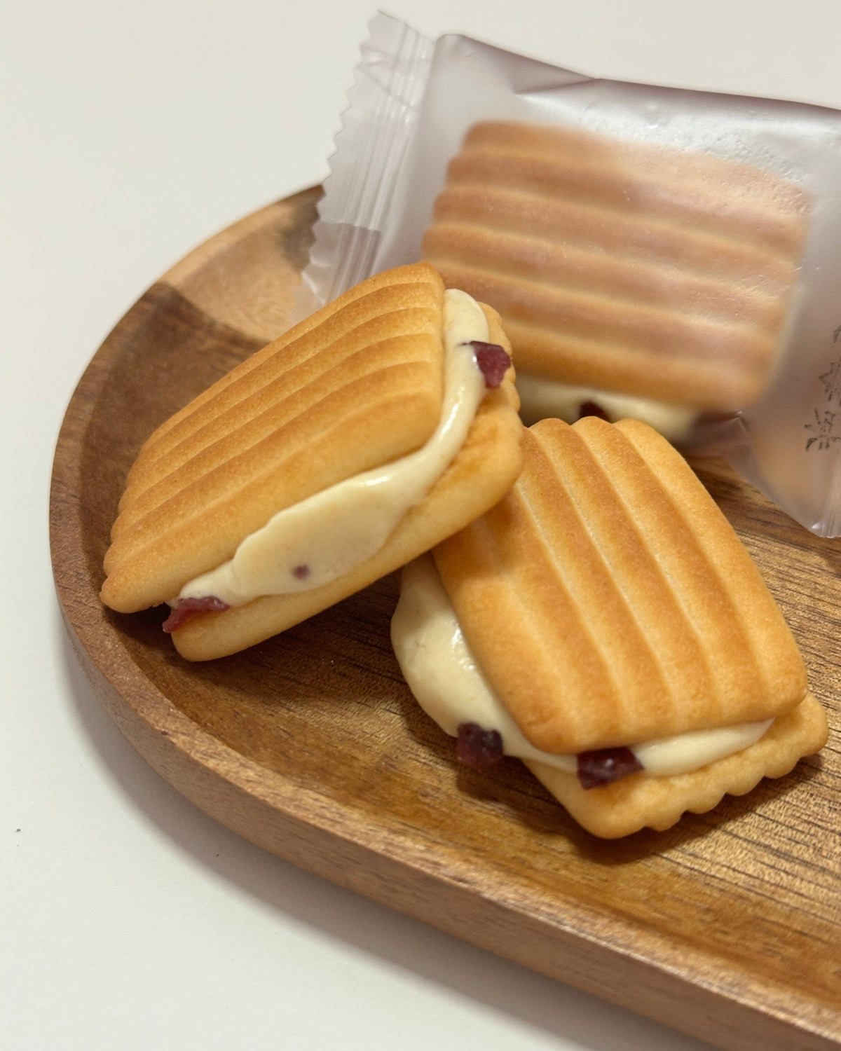 Two cookies sandwiches with cranberry snowflake filling on a wooden board