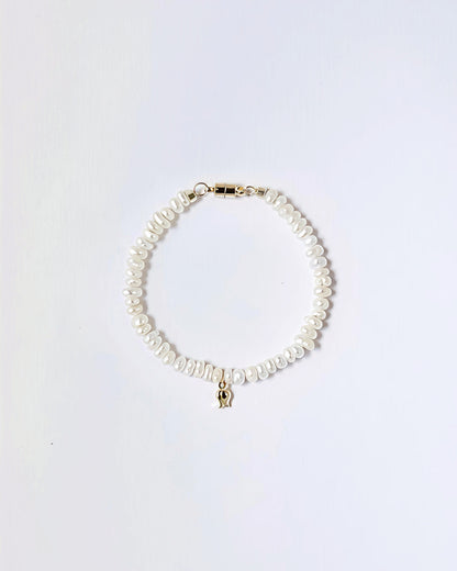 A delicate bracelet made of irregular white freshwater pearls with a small gold elephant charm and gold clasp, displayed on a clean white background.